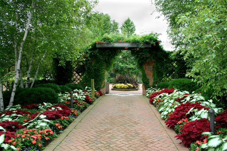 Formal garden with red brick pathway and rustic open gate