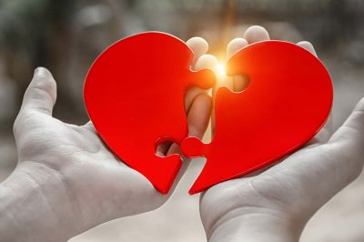 Two hand holding connecting two piece jigsaw love heart puzzle