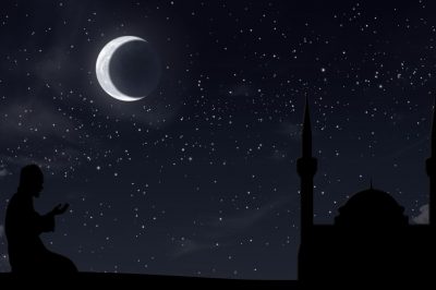 Muslim man standing in prayer at night, performing Tahajjud, with soft lighting creating a serene and peaceful atmosphere.