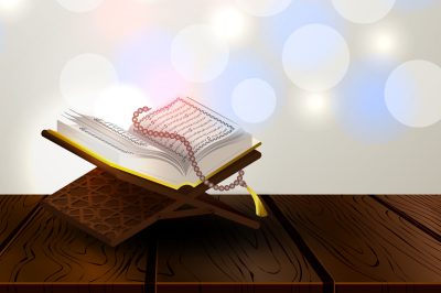 Open Qur&rsquo;an on a wooden stand with prayer beads placed over it.
