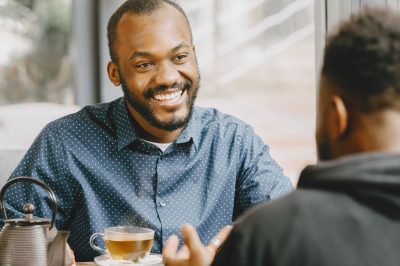 Smiling man in a blue polka dot shirt engaged in a friendly conversation
